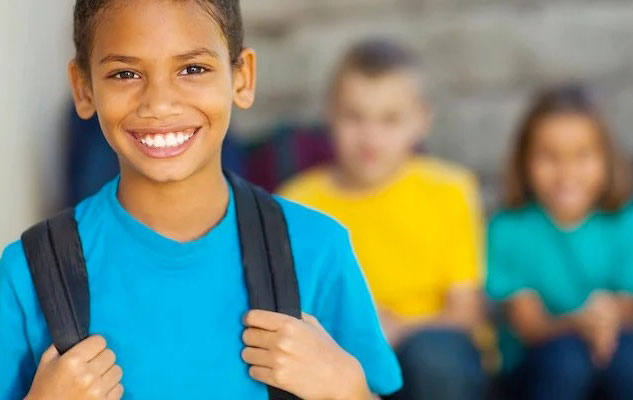 Un collégien sourit face à la caméra et devant ses camarades en arrière-plan